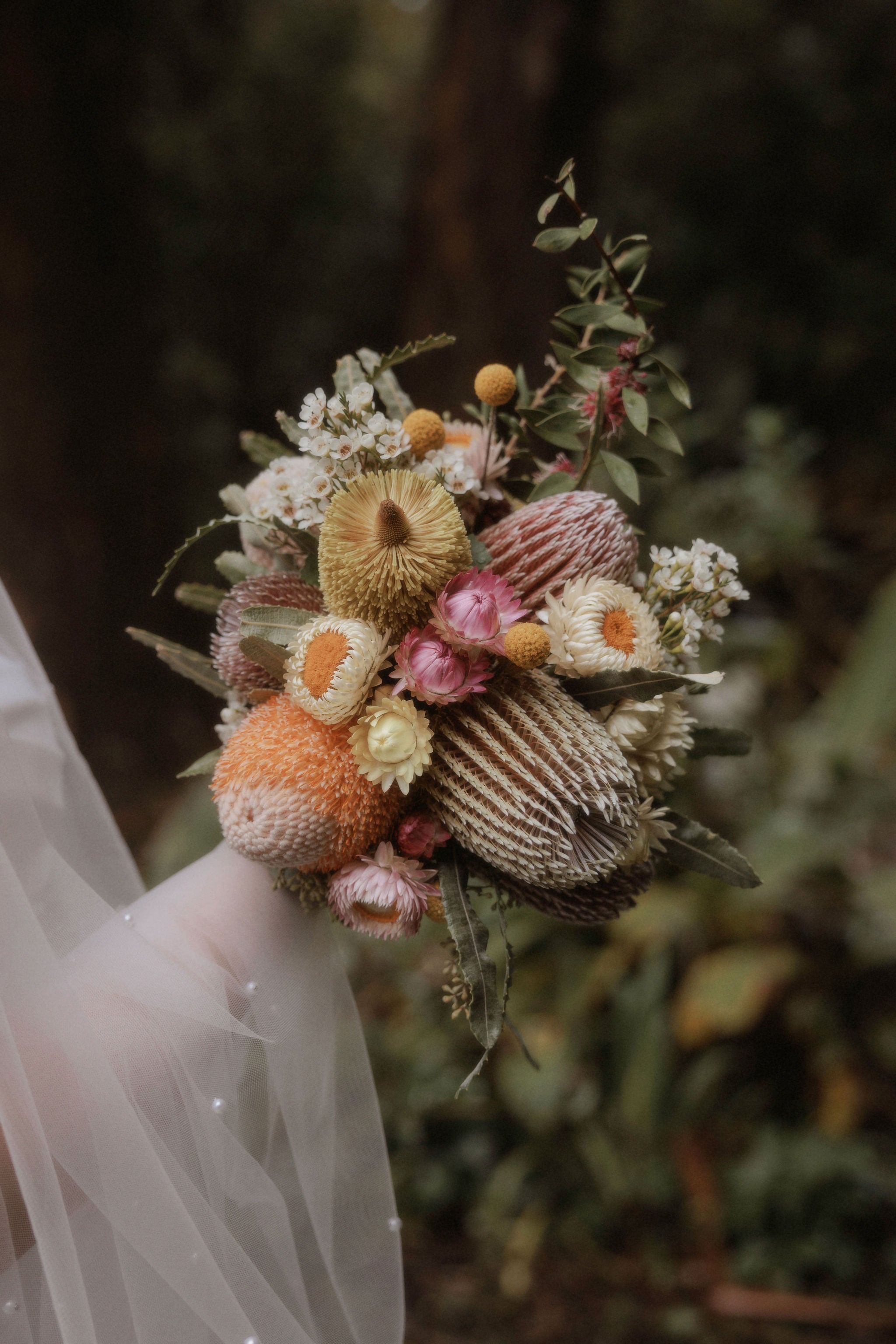 Bouquet of flowers held by a person with a blurred natural background. Image by Who Shot The Photographer