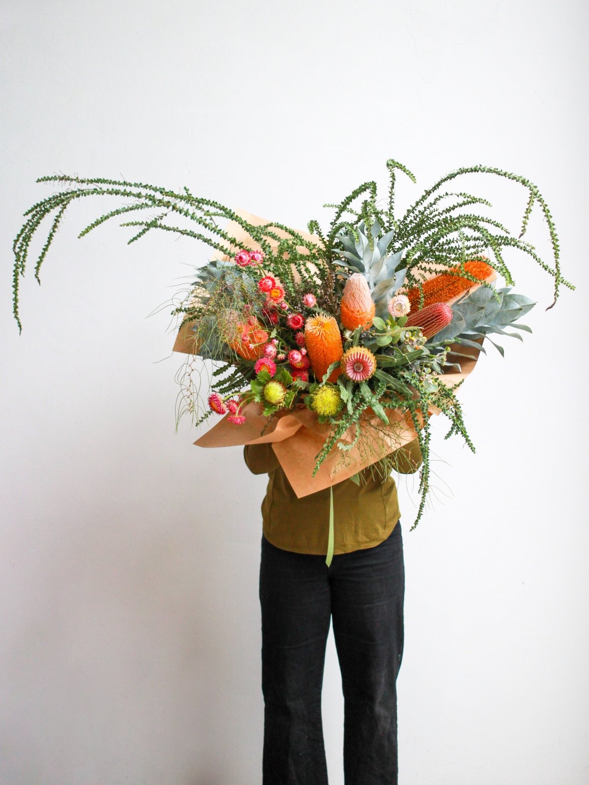 Person holds an extra large bush bouquet of native flowers