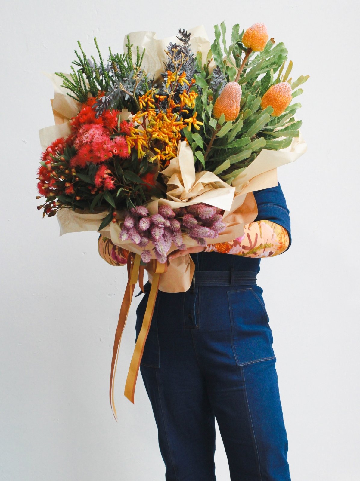 Multiple bunches of Australian native flowers gift wrapped as one large bunch and tied with ribbon for delivery. 