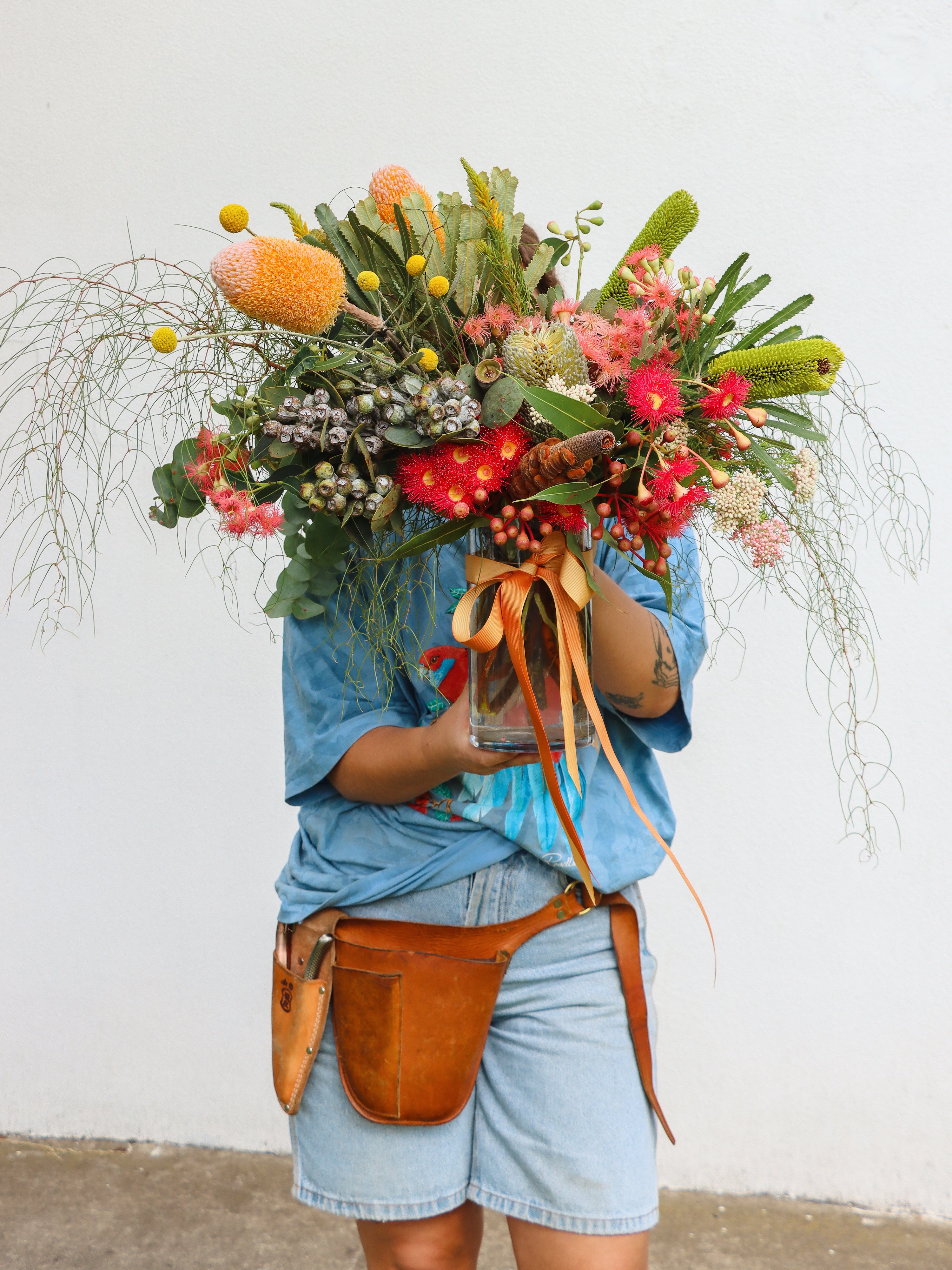 Person holding a large, colorful bouquet of  native flowers against a white background. 